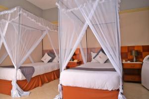 2 bedden met klamboes in een kamer bij ESCAPE VILLAGE HOTEL in Yumbe