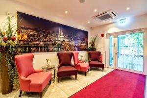 a waiting room with red chairs and a wall mural at CityClass Hotel am Heumarkt in Cologne