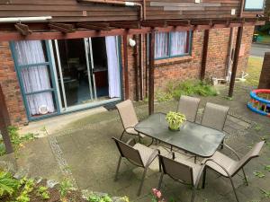 eine Terrasse mit einem Tisch und Stühlen sowie ein Gebäude in der Unterkunft Sunny holiday home Wellington in Wellington