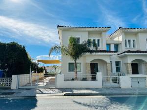 uma casa com uma palmeira em frente a uma piscina em coral bay beach villa em Pafos