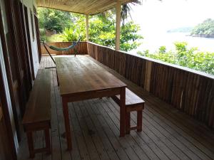 uma mesa de madeira num alpendre com vista para a água em Infinity-house with direct access to the beach em SantʼAna