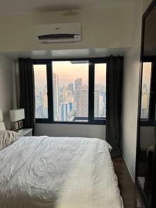 ein Schlafzimmer mit einem weißen Bett und einem großen Fenster in der Unterkunft My Hideaway@Air in Manila