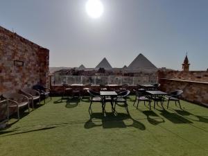 eine Gruppe von Tischen und Stühlen auf einem Dach mit Pyramiden in der Unterkunft dream pyramids view in Kairo