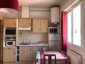 Elle comprend une petite cuisine avec des placards en bois et une fenêtre. dans l'établissement Résidence Natura, à Ax-les-Thermes