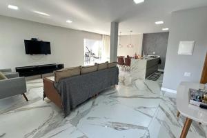 a living room with a couch and a television on a marble floor at Casa Retiro do Congo in Vila Velha