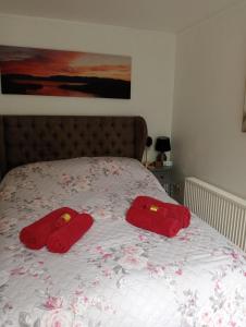 Dos toallas rojas en una cama con flores. en Relaxing secluded lodge couples getaway with hot tub en Eaton