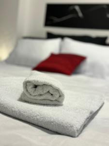ein weißes Handtuch auf einem Bett mit einem roten Kissen in der Unterkunft Ivanov Apartment in Bitola