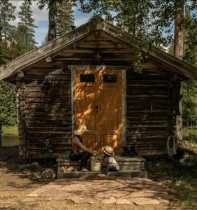 two women sitting outside of a small cabin at Cabin by Byske river surrounded by the forest in Byske