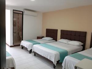 a bedroom with two beds and a shower at Hotel Exito Barranquilla in Barranquilla