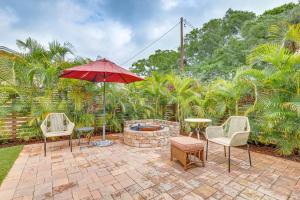 a patio with chairs and an umbrella and a fire pit at Tampa Home with Fire Pit, Grill, Cornhole and More! in Tampa