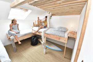 a man and a woman sitting on bunk beds in a room at SURF HOSTEL BIARRITZ in Biarritz