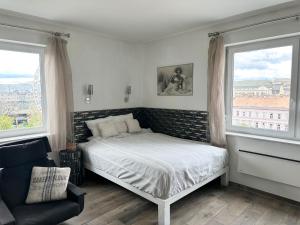 ein Schlafzimmer mit einem Bett, einem Stuhl und zwei Fenstern in der Unterkunft Vista Suites 1-2 in Budapest
