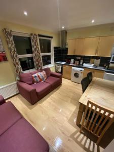 ein Wohnzimmer mit einem lila Sofa und einem Tisch in der Unterkunft 4 Bedroom Apartment & 2 Bedroom apartment in London