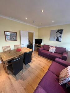 un salon avec un canapé violet et une table dans l'établissement 4 Bedroom Apartment & 2 Bedroom apartment, à Londres