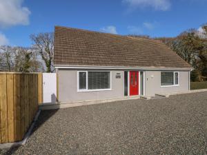 una casa blanca con una puerta roja y una valla en Wychwood en Haverfordwest