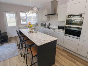 a kitchen with white cabinets and a marble counter top at Wychwood in Haverfordwest
