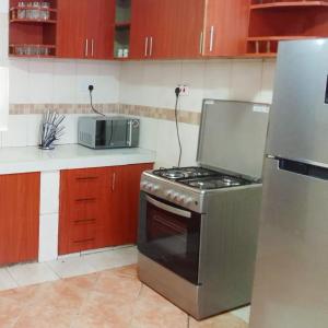 Il comprend une cuisine équipée d'une cuisinière et d'un réfrigérateur. dans l'établissement Sofitel Executive 4 bedrooms Milimani, à Kisumu
