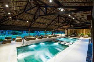 einen Innenpool mit Stühlen und einen großen Pool in der Unterkunft Casa 3A Tivoli Ecoresidences in Praia do Forte