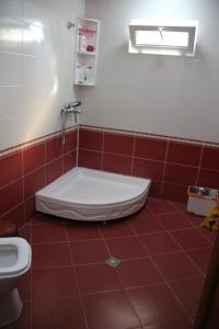 La salle de bains est pourvue de carrelage rouge, d'une baignoire et de toilettes. dans l'établissement Qabala_Renting_houses near the mountain, à Qabala