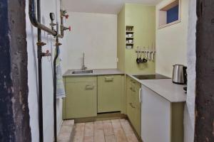 uma cozinha com armários verdes e brancos e um lavatório em Ferien im Baudenkmal Toggenburg em Krummenau