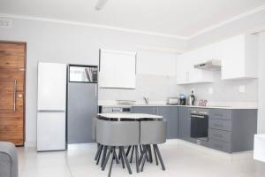 una cocina con electrodomésticos blancos y armarios grises en Summer Square, Umhlanga Ridge, en Durban