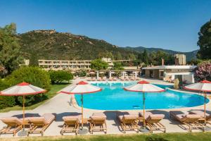 a swimming pool with chairs and umbrellas at Is Molas Resort in Pula