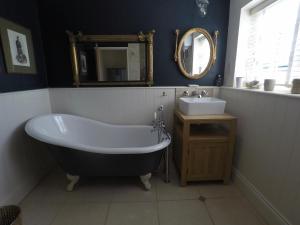 a bathroom with a bath tub and a sink at Laurel Cottage in Exmouth +3 photos
