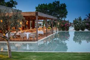 a restaurant with tables and chairs next to a swimming pool at Is Molas Resort in Pula