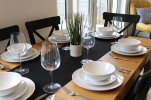 a wooden table with plates and wine glasses on it at 4 Bedroom Getaway New Forest in New Milton