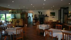 a restaurant with tables and chairs and a kitchen at Hotel Zur alten Schmiede in Schaprode