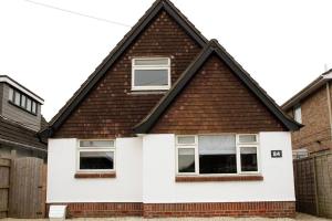 a white house with a brown roof at 4 Bedroom Getaway New Forest in New Milton