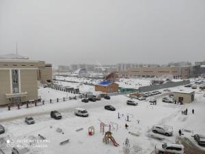 een parkeerplaats bedekt met sneeuw met geparkeerde auto's bij Уютная квартира на Кадыр-Мырза Али in Oral