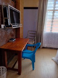 a wooden table with a blue chair and a television at Oasis Hotel and Guest House. Voi in Voi