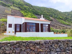 a small house on a hill with a stone wall at Casa dos Magalhães in Vila do Porto