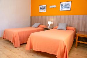 2 letti in una camera con pareti arancioni di RVHotels Condes del Pallars a Rialp
