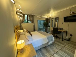 Habitación de hotel con cama, escritorio y TV. en Echo Mountain Inn en Thabazimbi