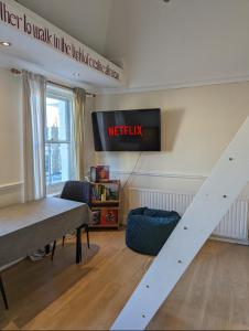 a room with a table and a television on a wall at 2 bed in the Heart of Stoke Newington in London