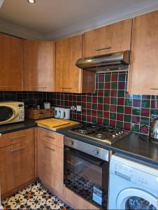 a kitchen with wooden cabinets and a stove top oven at 2 bed in the Heart of Stoke Newington in London
