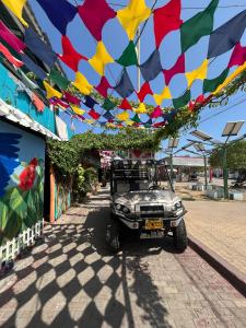 an old jeep parked under a colorful arch with flags at Posada Amaripucci in San Andrés