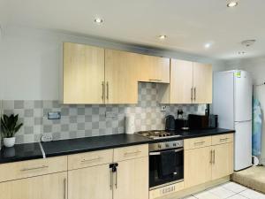 a kitchen with wooden cabinets and a white refrigerator at Falcon - 2 Bedroom Ground floor flat in Central London in London