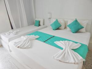 2 camas blancas con almohadas verdes en una habitación en POSADA RANCHO DELFIN, en El Yaque