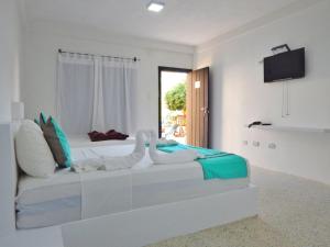 a white bedroom with a bed and a window at POSADA RANCHO DELFIN in El Yaque