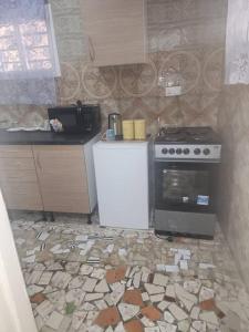 a kitchen with a stove and a tile floor at Malikia Apartment 1 in Brusubi