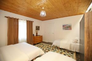 1 dormitorio con 2 camas y techo de madera en Guest House Bashaj, en Bashaj