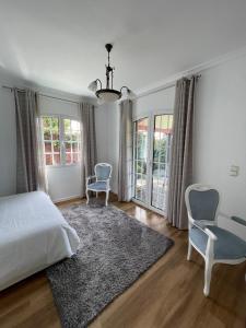ポンタ・ド・ソルにあるCasa Cabozのベッドルーム1室(ベッド1台、椅子2脚、窓付)