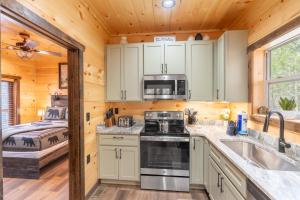 a kitchen with a stove and a sink and a bedroom at Hawks Nest Mountain Cabin in Sevierville