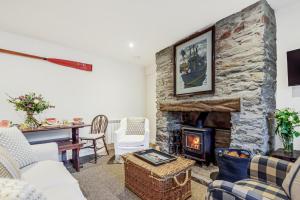 ein Wohnzimmer mit einem Steinkamin und einem Tisch in der Unterkunft Cottages in Tranquil Hamlet in Salcombe