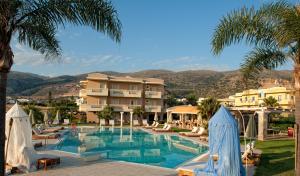 マリアにあるSocrates Hotel Malia Beachのヤシの木と建物が並ぶリゾートのプールを利用できます。