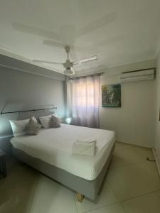 ein Schlafzimmer mit einem weißen Bett und einem Fenster in der Unterkunft Las Palmeras by Graziano VIP in Boca Chica