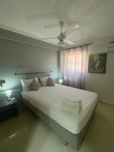 Schlafzimmer mit einem großen weißen Bett und einem Deckenventilator in der Unterkunft Las Palmeras by Graziano VIP in Boca Chica